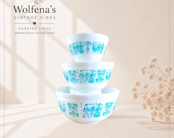 May include: Three white vintage bowls stacked, each adorned with a turquoise folk art design. The bowls feature a variety of figures and patterns. The image includes the text "Wolfena's Vintage Vibes".