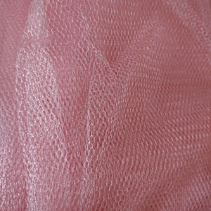 May include: Pink tulle fabric with a fine mesh pattern. The fabric is soft and delicate, and it has a slight sheen.