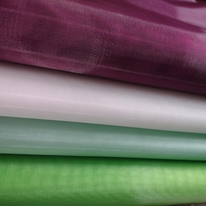 May include: Four layers of sheer fabric in different colors. The top layer is a deep purple, followed by a light pink, a light blue, and a green layer.
