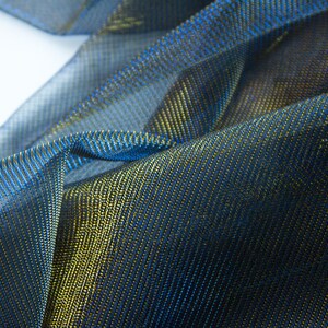 May include: Close-up of a blue and gold metallic fabric with a textured, woven pattern.