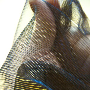 May include: A close-up of a black and gold fabric with a shimmery, iridescent finish. The fabric has a fine mesh texture and is draped over a surface.