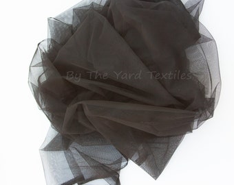 Peut inclure: Tulle noir, un tissu léger et transparent avec une texture délicate. Le tissu est plié et drapé, mettant en valeur sa nature douce et fluide.