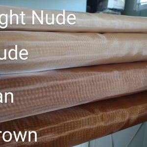 May include: Four rolls of sheer fabric in different shades of brown. The rolls are labelled "Light Nude", "Nude", "Tan", and "Brown".