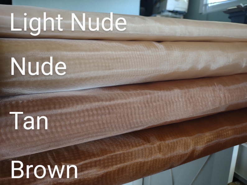 May include: Four rolls of sheer fabric in different shades of brown. The rolls are labelled "Light Nude", "Nude", "Tan", and "Brown".
