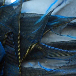 May include: Blue and gold metallic mesh fabric with a fine, woven texture. The fabric is draped and folded, showing the shimmery effect of the metallic threads.