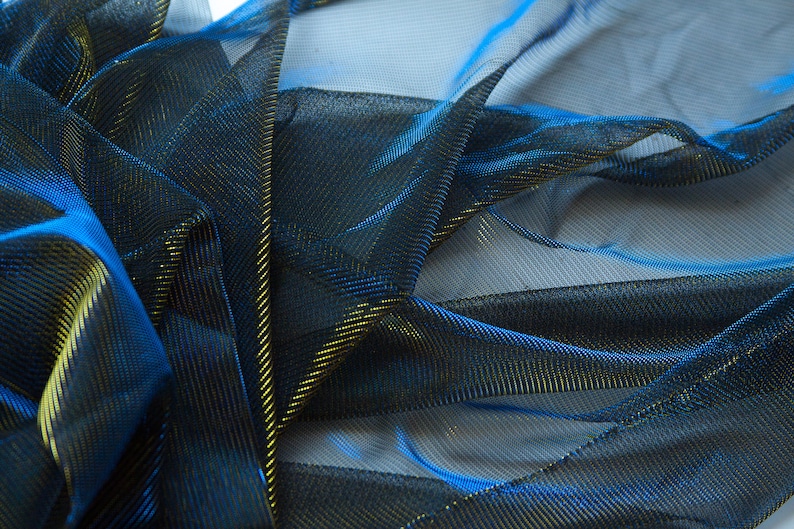 May include: Blue and gold metallic mesh fabric with a fine, woven texture. The fabric is draped and folded, showing the shimmery effect of the metallic threads.