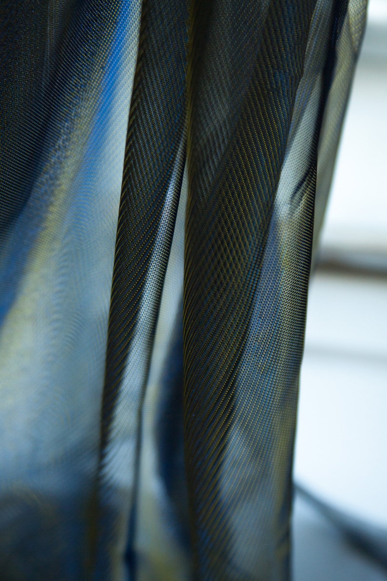 May include: Close-up of a sheer black curtain with a subtle gold pattern. The fabric is translucent, allowing light to filter through.