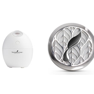 May include: Two aromatherapy diffusers. One is a white, egg-shaped essential oil diffuser with the text "Young Living" and a leaf logo. The other is a silver-colored, round diffuser with a leaf design.