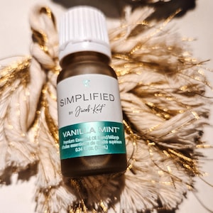 May include: A small, clear glass bottle with a white cap, labelled "SIMPLIFIED by Jacob Kait VANILLA MINT™ Premium Essential Oil Blend/Mélange huiles essentielles de qualité supérieure 0.34 fl oz (10 ml)"