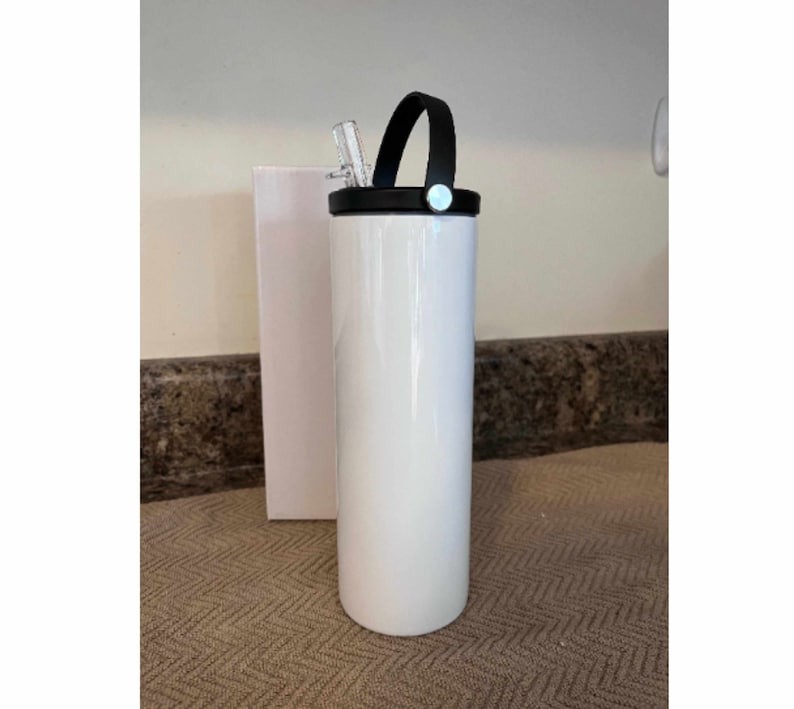 May include: White stainless steel tumbler with a black lid and a black handle. The tumbler has a straw sticking out of the lid.