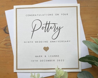 May include: A white card with a brown border and a gold heart. The card says "Congratulations on your Pottery Ninth Wedding Anniversary Mark & Leanne 10th December 2022".