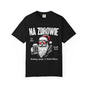 Puede incluir: Camiseta negra con un gráfico de Papá Noel con gafas de sol y una cerveza. El texto "NA ZDROWIE" está encima del gráfico de Papá Noel, con "Sip Slow" y "Laugh Hard" a ambos lados. Debajo del gráfico está escrito "Holiday Spirits & Polish Cheers."