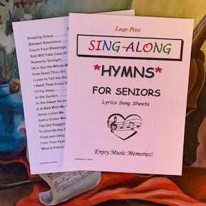May include: A pink sheet of paper with the words "Sing-Along Hymns for Seniors" in large, colourful letters. The sheet also includes the words "Lyrics Song Sheets" and "Enjoy Music Memories!" in smaller letters. There is a musical note heart symbol in the centre of the sheet.