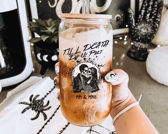 May include: A glass jar with a bamboo lid and a clear glass straw. The jar is filled with a brown liquid and has a black and white graphic of a skeleton couple with the text "Till Death Do Us Part" and "Mr. & Mrs."