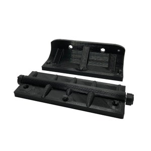 May include: Black 3D-printed hardware components. The image shows a base with a threaded rod and a curved top piece. The base has multiple mounting holes and raised, curved elements. The top piece has two mounting holes.
