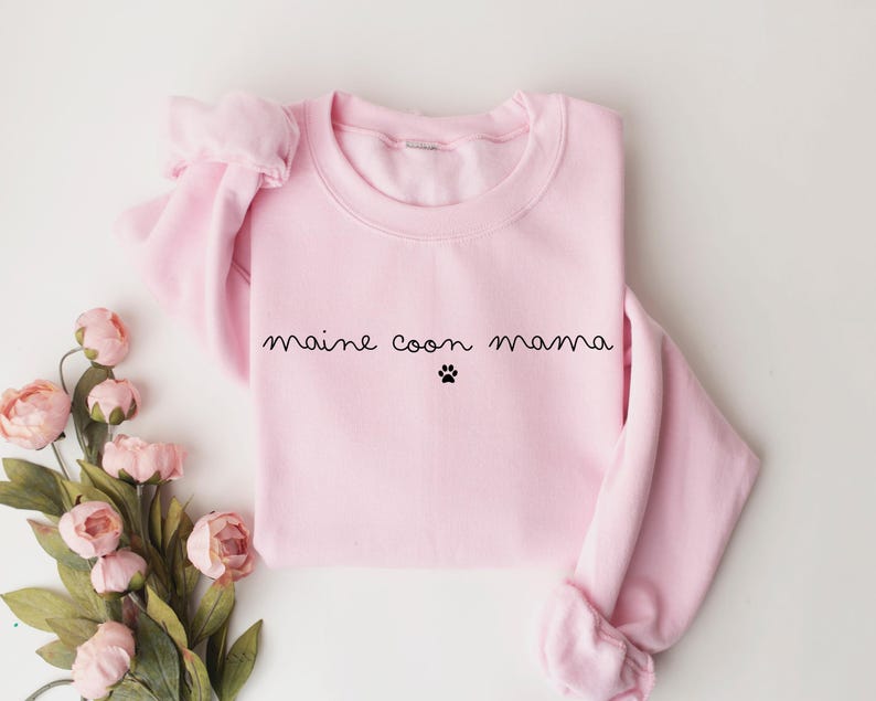 May include: Pink sweatshirt with the text "maine coon mama" and a paw print.
