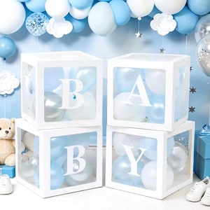 May include: White square boxes with transparent sides, each displaying a letter spelling "BABY" with blue and white balloons inside. The boxes are decorated with blue and white balloons, clouds, and stars, creating a festive atmosphere.