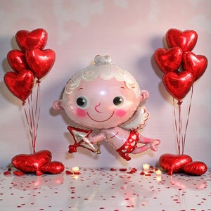 May include: A Valentine's Day scene featuring a large Cupid-shaped balloon with a bow and arrow, surrounded by red heart-shaped balloons. The Cupid balloon is pink with white hair and wings. Red heart-shaped balloons are arranged in clusters.