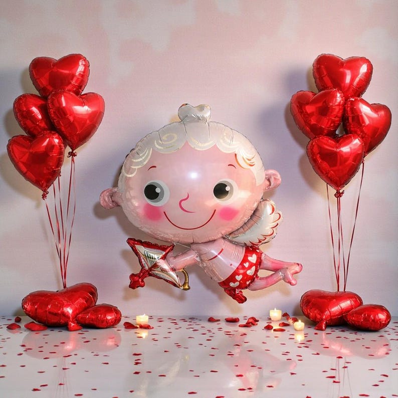 May include: A Valentine's Day scene featuring a large Cupid-shaped balloon with a bow and arrow, surrounded by red heart-shaped balloons. The Cupid balloon is pink with white hair and wings. Red heart-shaped balloons are arranged in clusters.