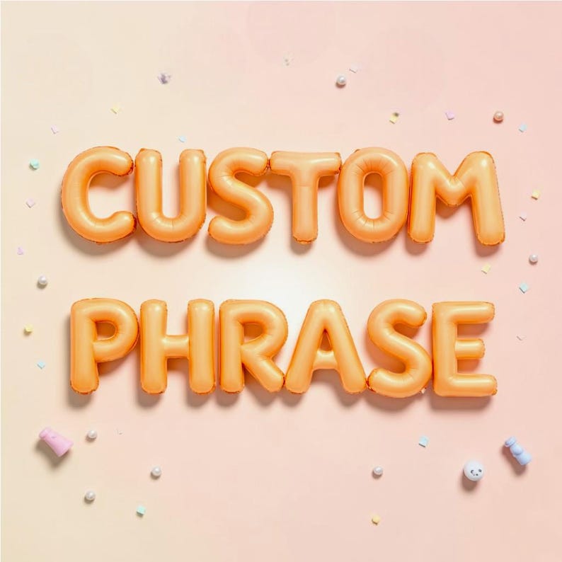 May include: Orange inflatable balloons spelling out "CUSTOM PHRASE" on a light pink background. The balloons are arranged in two rows, with "CUSTOM" above "PHRASE". Small confetti and decorative elements are scattered around the text.