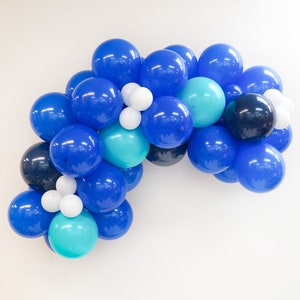 K&ouml;nnte beinhalten: Eine blaue, t&uuml;rkisfarbene und wei&szlig;e Ballon-Girlande. Die Girlande besteht aus verschiedenen Gr&ouml;&szlig;en von Ballons. Die Ballons sind in einer Halbkreisform angeordnet.