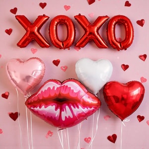 May include: Red foil balloons spelling "XOXO" are displayed above a collection of heart and lip-shaped balloons. A pink background is decorated with small red heart cutouts, creating a festive and romantic atmosphere.