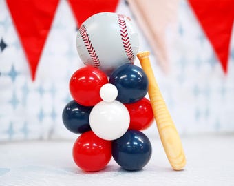 Op de afbeelding: Een ballon centerpiece met een baseballthema met rode, witte en blauwe ballonnen, een baseball en een houten knuppel.