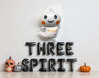 May include: A Halloween-themed display featuring a white ghost balloon with the word "BOO!" and black balloon letters spelling "THREE SPIRIT." Decorative elements include a skull, a silver pumpkin, and an orange pumpkin.