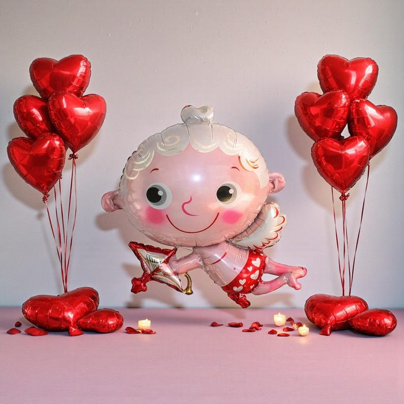 May include: A Valentine's Day themed image featuring a large Cupid-shaped balloon with a bow and arrow, surrounded by red heart-shaped balloons. The Cupid balloon is pink and white, with a smiling face and small wings. Several heart-shaped balloons are arranged in clusters.