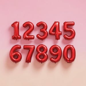 May include: Red foil number balloons from 0 to 9 arranged on a pink background. The numbers are inflated and have a shiny metallic finish. Ideal for birthday parties, anniversaries, or other celebratory events.