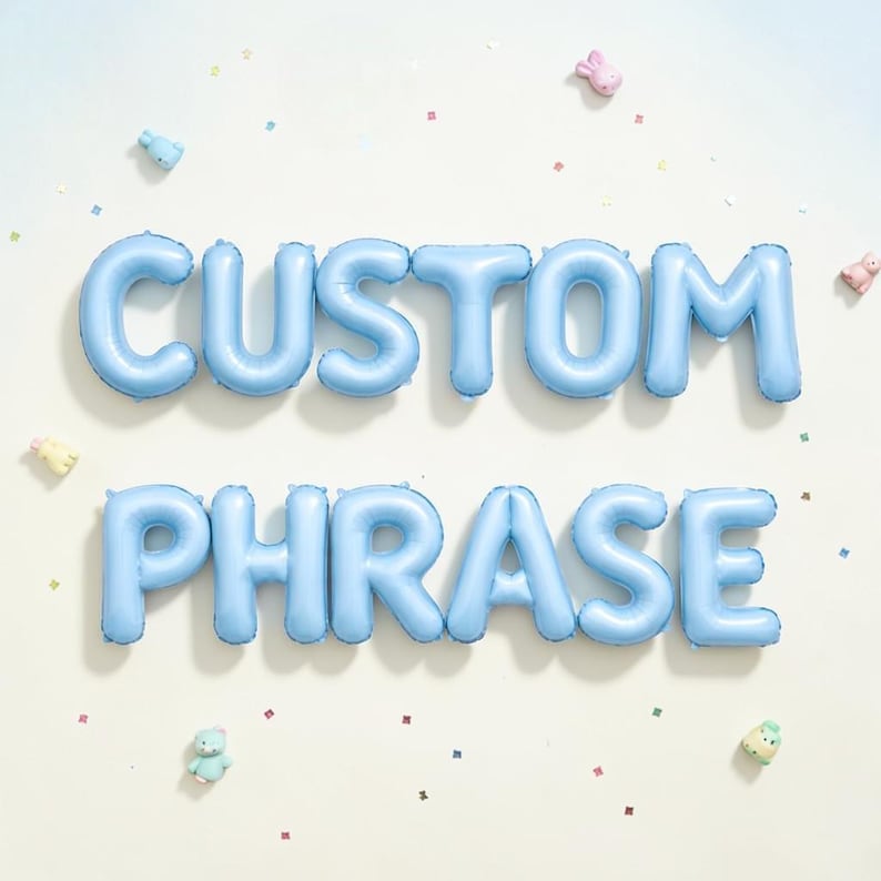 May include: Light blue foil balloons spelling out "CUSTOM PHRASE" against a white background. The balloons are arranged in two rows. Small, colorful confetti and toy animals are scattered around the balloons.