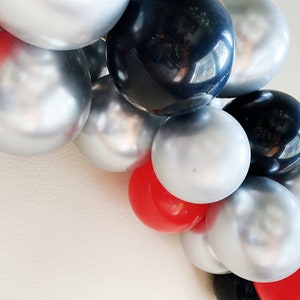 May include: A balloon garland with silver, black, and red balloons. The balloons are arranged in a cascading pattern.