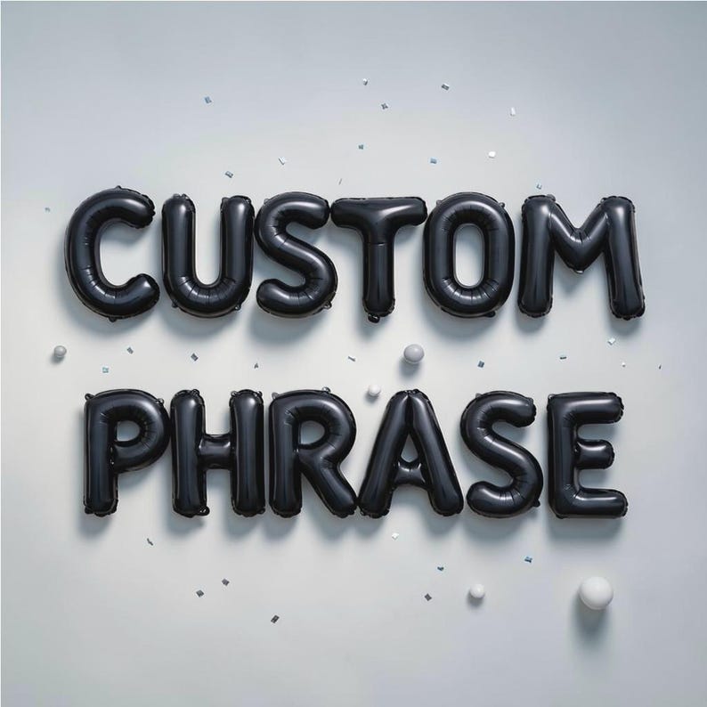May include: Black foil balloons spelling out "CUSTOM PHRASE" against a white background. The balloons are arranged in two lines, with the word "CUSTOM" above "PHRASE". Small white spheres and confetti are scattered around the balloons.