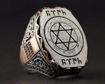 May include: A silver ring with a gold band and a star of David design. The ring is engraved with the words "AYINH" and Arabic script.