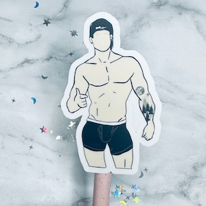 May include: A black and white illustration of a person with a forest scene tattoo on their arm. The person is wearing black underwear and a baseball cap.