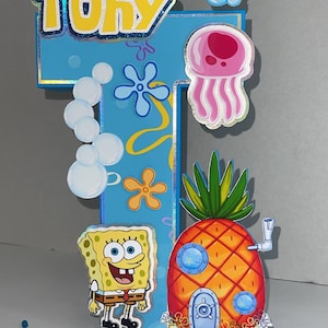 May include: A colorful birthday decoration featuring the name "Tony" in yellow letters on a blue background. Includes cartoon images of SpongeBob SquarePants, a pineapple house, and a jellyfish.