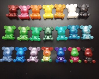May include: A collection of 18 small, colorful, resin bear figurines. The bears are arranged in two rows, with each bear facing forward. The bears are all different colors, including red, orange, yellow, green, blue, purple, and black.