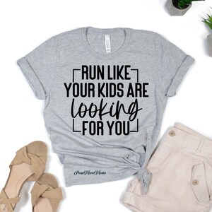 K&ouml;nnte beinhalten: Graues T-Shirt mit schwarzem Text, der "Lauf, als w&uuml;rden deine Kinder nach dir suchen" lautet.