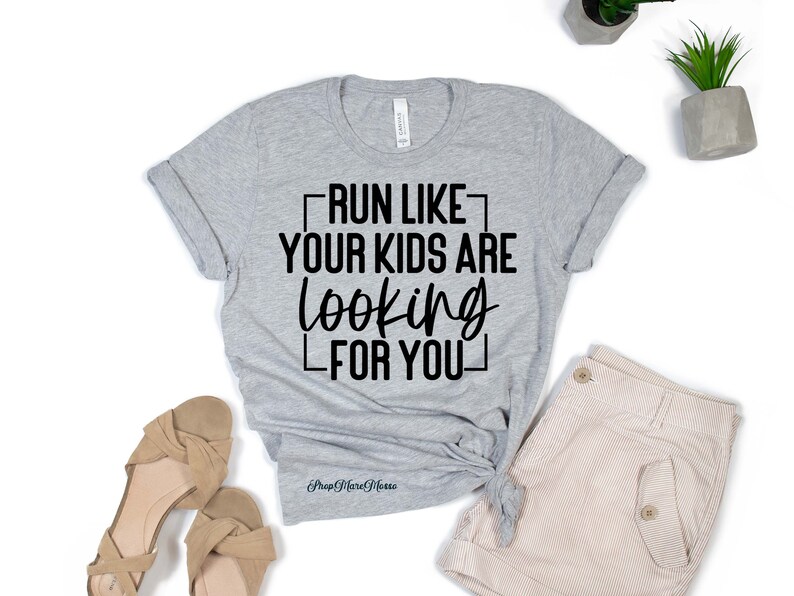 K&ouml;nnte beinhalten: Graues T-Shirt mit schwarzem Text, der "Lauf, als w&uuml;rden deine Kinder nach dir suchen" lautet.