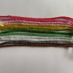 May include: A set of ten colourful beaded bracelets, each with a different colour and pattern. The bracelets are made with small, round beads and are tied with string.