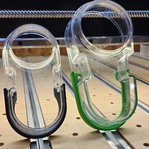 May include: Two clear plastic hooks with black and green trim. The hooks are designed to hang items.