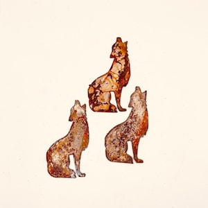 May include: Three rusty metal wolf silhouettes, each with a different pose, are arranged in a triangular formation on a white background.