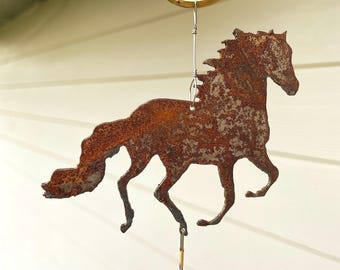 May include: A rusty metal horse silhouette wind chime with a pink glass bead hanging from the bottom. The horse is in a running pose with its mane flowing in the wind.