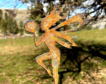 May include: A rustic metal fairy garden ornament with a ball in one hand and outstretched wings. The fairy is made of weathered metal with a rusty orange hue. A string of colorful glass beads hangs above the fairy.
