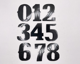 May include: Black vinyl numbers 0 through 8, with a glossy finish. The numbers are arranged in three rows, with the first row containing 0, 1, and 2, the second row containing 3, 4, and 5, and the third row containing 6, 7, and 8.