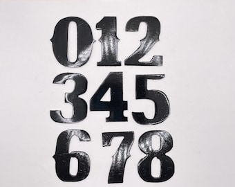 May include: Black vinyl numbers 0 through 8, with a glossy finish. The numbers are arranged in three rows, with the first row containing 0, 1, and 2, the second row containing 3, 4, and 5, and the third row containing 6, 7, and 8.