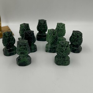 May include: A collection of nine green owl figurines carved from jade. The owls are all different sizes and have intricate details.