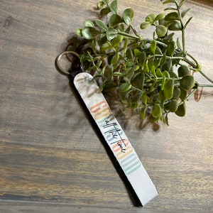 May include: A white keychain with a black strap and a colorful design. The design features a rainbow pattern with the text "Good Vibes all the time".