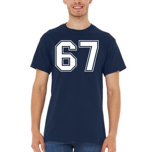 May include: Navy blue t-shirt with the number 67 in white, outlined in navy. The number is large and centered on the shirt. The shirt is a crew neck style.