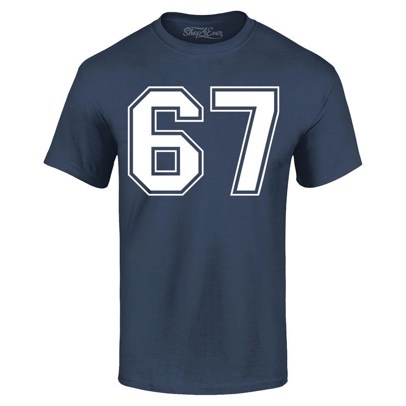 May include: Navy blue t-shirt with the number "67" in white block lettering. The number is outlined in white. The shirt has a crew neck and short sleeves. The brand name "Shop4Ever" is printed on the upper right.